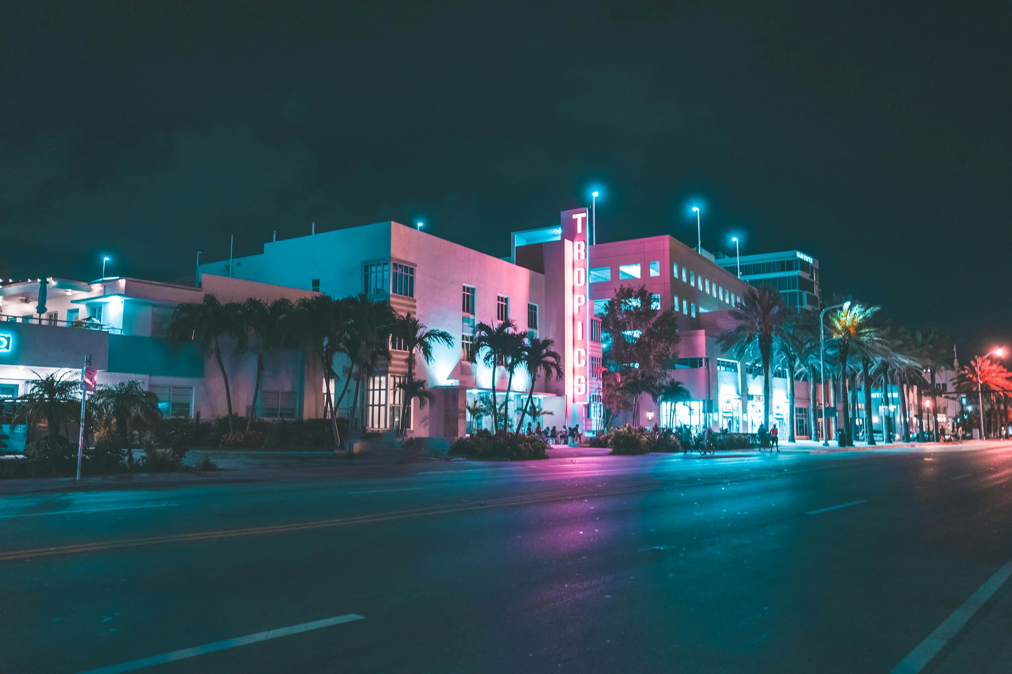 Enseigne au néon Tropics d'un hôtel bordé de palmiers, de nuit